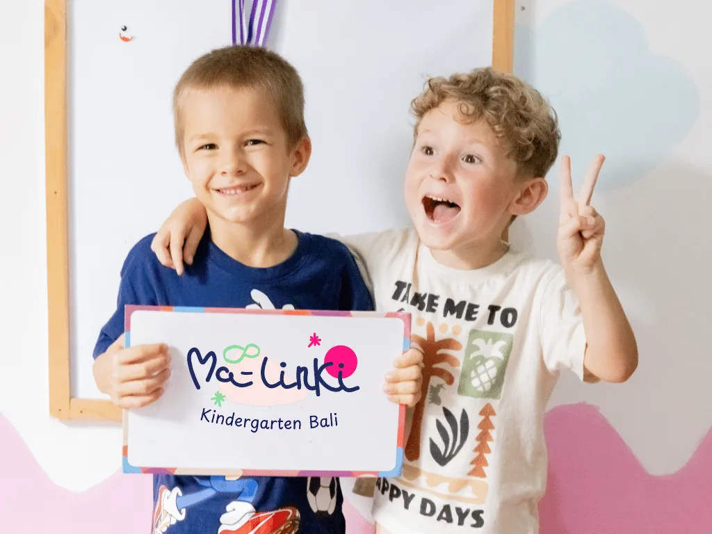 Two boys smiling and holding a Ma-linki Kindergarten Bali sign